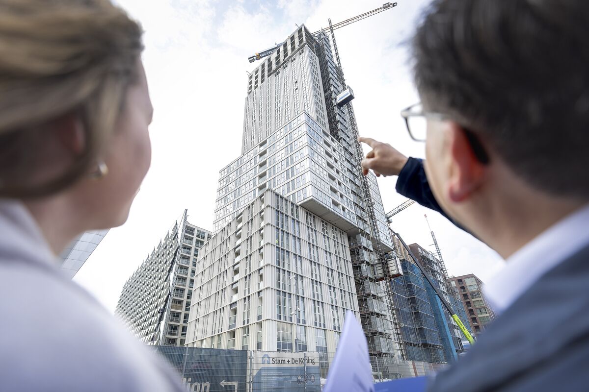 Hombre y mujer mirando fijamente un edificio alto y gris en construcción.