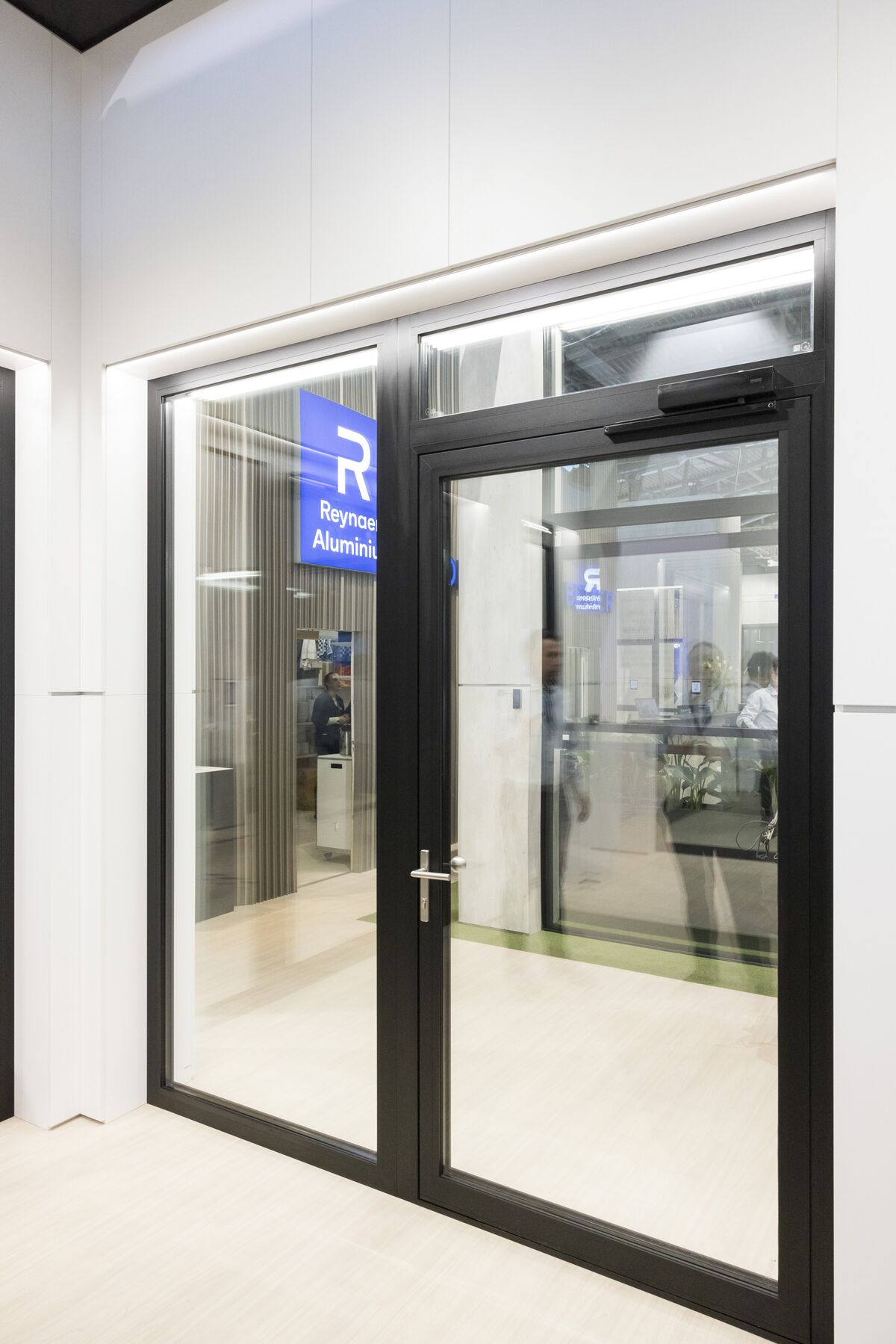 Puerta de aluminio negro en un stand de feria brillante de Reynaers Aluminium.