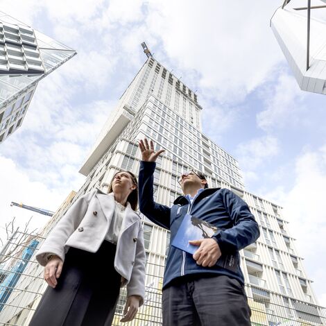Hombre y mujer señalando y hablando sobre edificios de gran altura.