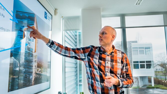 Hombre con camisa a cuadros apuntando a la pantalla de presentación.