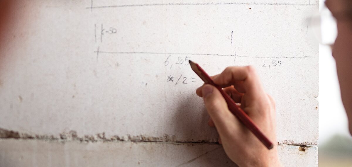 Hombre escribiendo con lápiz en la pared de hormigón del sitio de construcción.