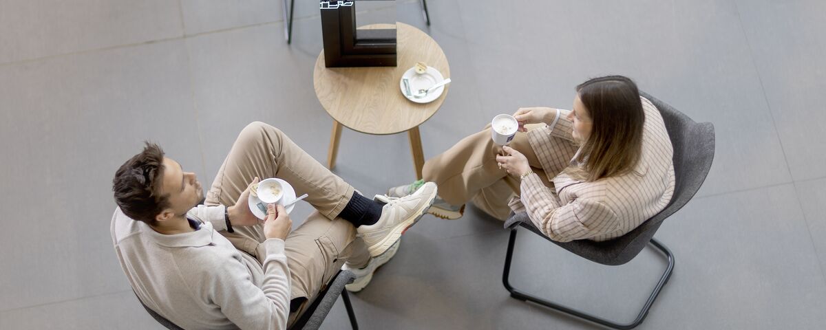 Vista superior de un hombre y una mujer sentados en una mesa tomando café.