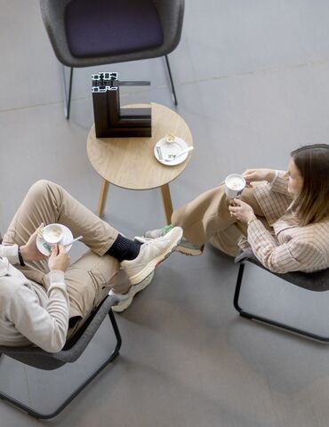 Vista superior de un hombre y una mujer sentados en una mesa, tomando café.