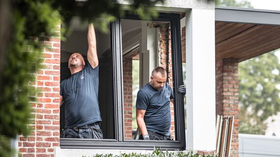 Dos instaladores colocando nuevos perfiles de aluminio en vivienda reformada.