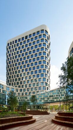 Edificio de oficinas futurista de color blanco con árboles al lado.